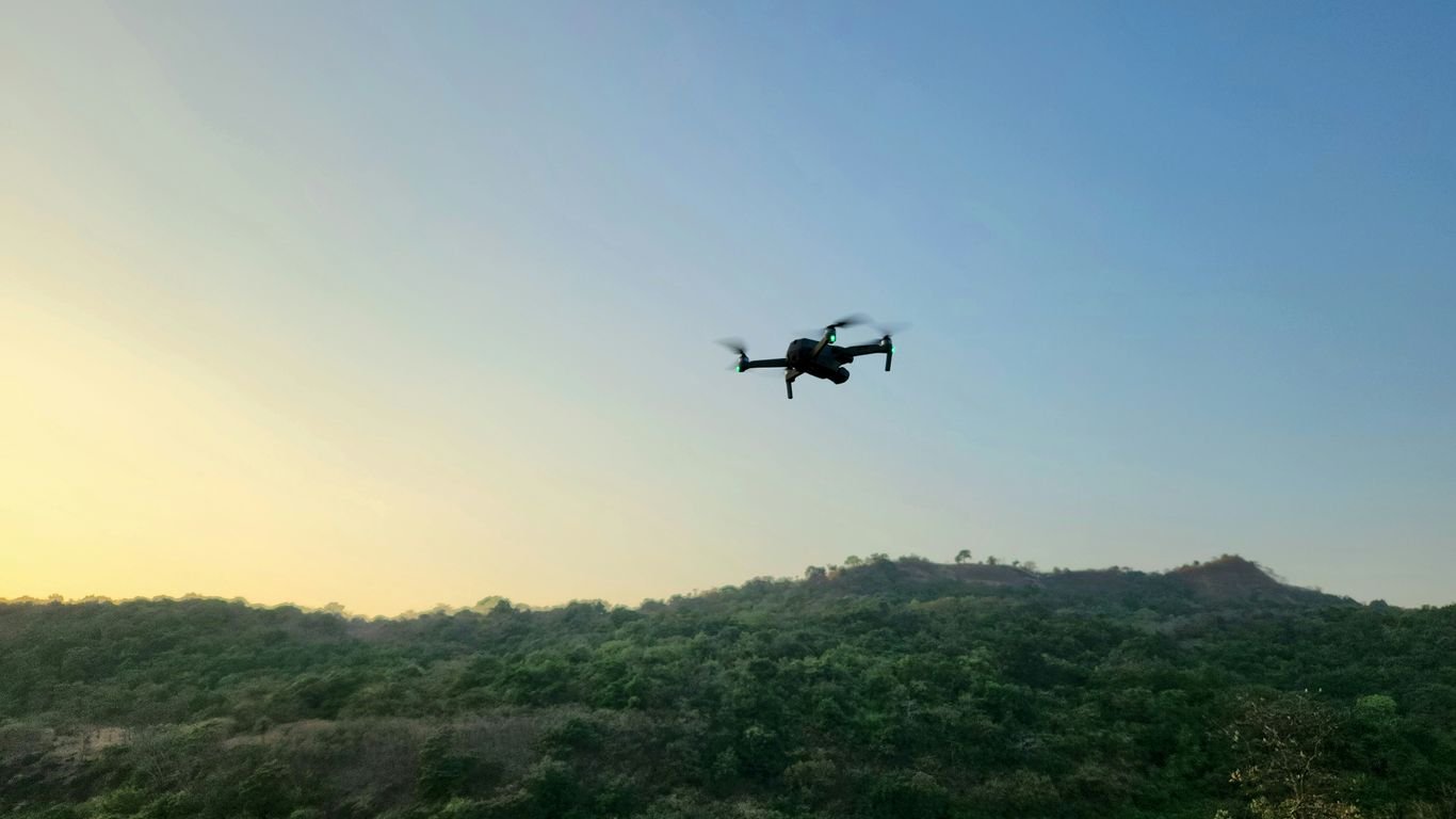 a small plane flying over a lush green hillside