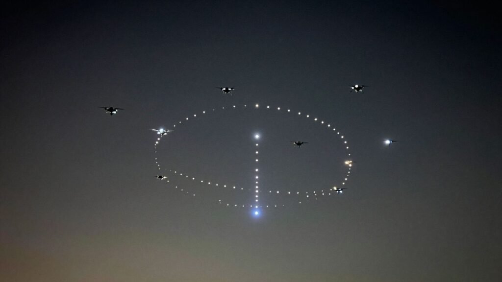 Drones in formation creating light patterns in the night sky.