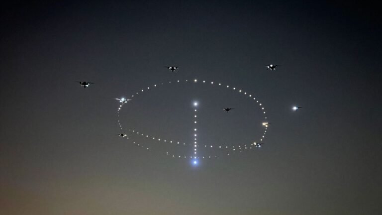 Drones in formation creating light patterns in the night sky.