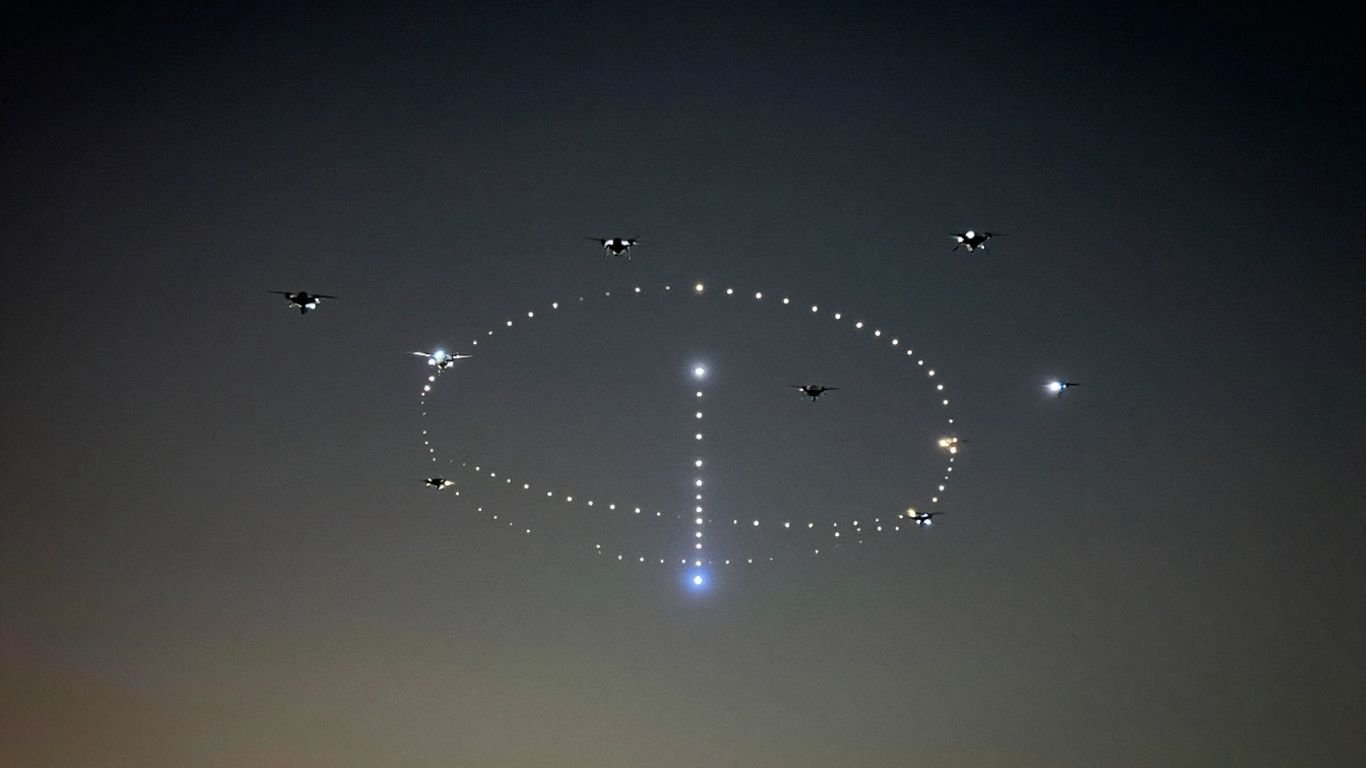 Drones in formation creating light patterns in the night sky.